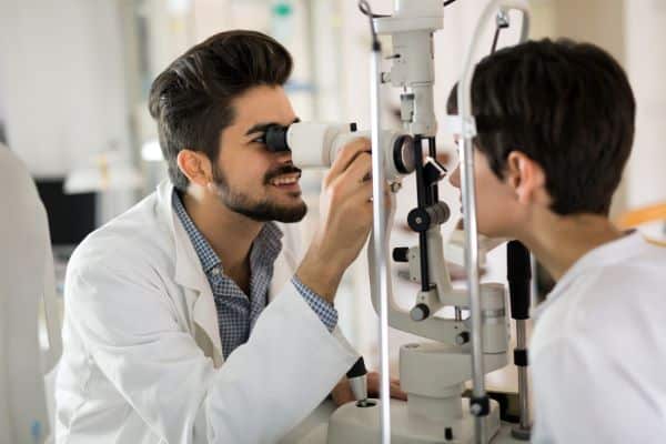 Médico realizando exame oftalmológico em rapaz.