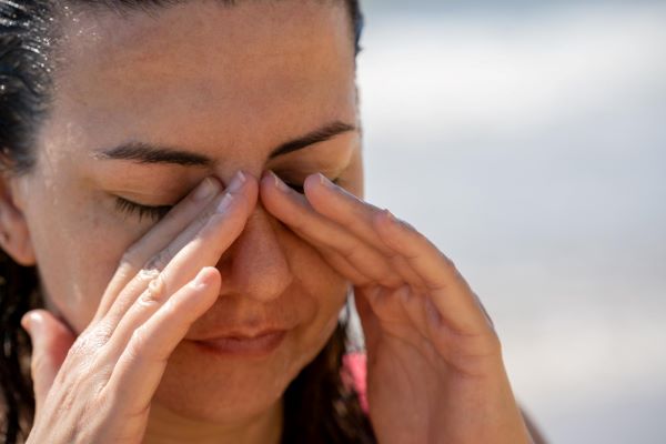 Mulher coçando os olhos com sintomas de conjuntivite viral