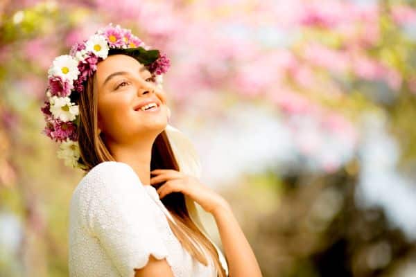 Jovem bonita com coroa de flores em um cenário de primavera