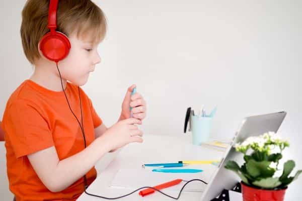Criança daltônica em idade escolar realizando atividades por meio do uso de dispositivo eletrônico.