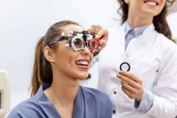Oftalmologista examinando mulher, pós-cirurgia ocular,  para verificar a visão na clínica oftalmológica.

