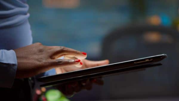 Mulher negra digitando em um tablet.