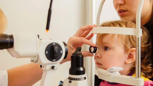 Saúde infantil - menina com a mãe na clínica oftalmológica verifica a visão.