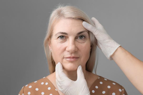 Mulher loira e com olhos azuis está sendo avaliada por especialista para correção de ptose palpebral.