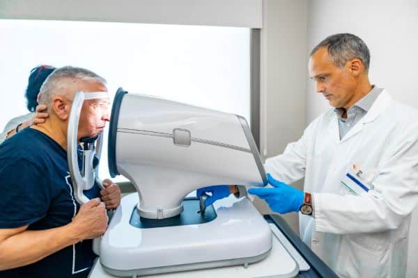 Senhor de idade realiza exame para detectar glaucoma em um instrumento oftalmológico a laser.