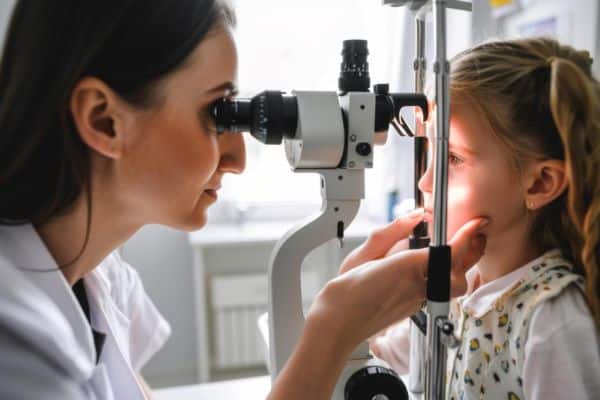 Oftalmologista realiza exame nos olhos de uma menininha, a fim de detectar se há algum tipo de problema ocular infantil.