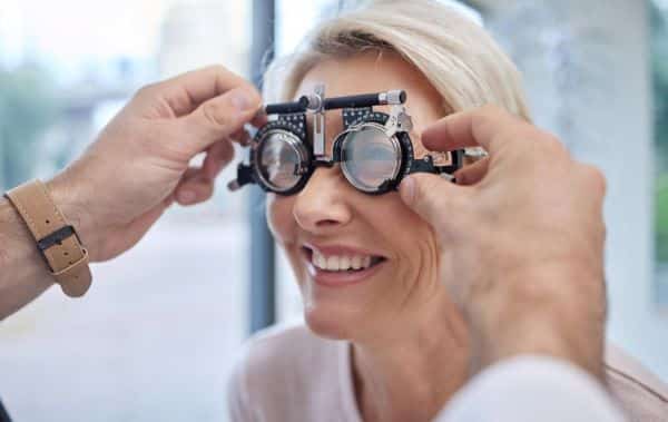 Mulher realizando exame oftalmológico para detectar doença ocular como o glaucoma.
Oftalmologista testa o grau da paciente que sorri satisfeita.