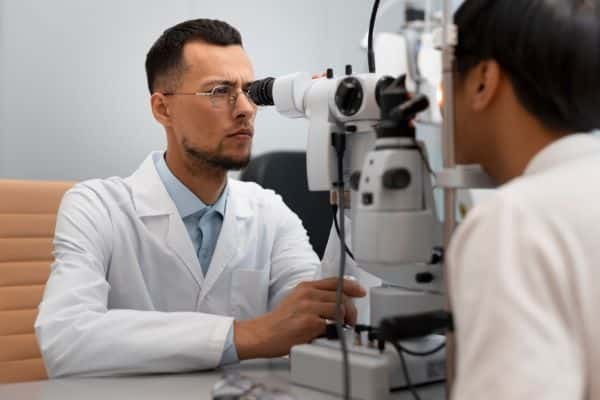 Paciente numa clínica oftalmológica moderna realizando exame pós-cirurgia de córnea.