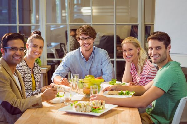 Jovens - 3 homens e 2 mulheres - almoçando comida saudável em seu ambiente de trabalho durante o intervalo. 