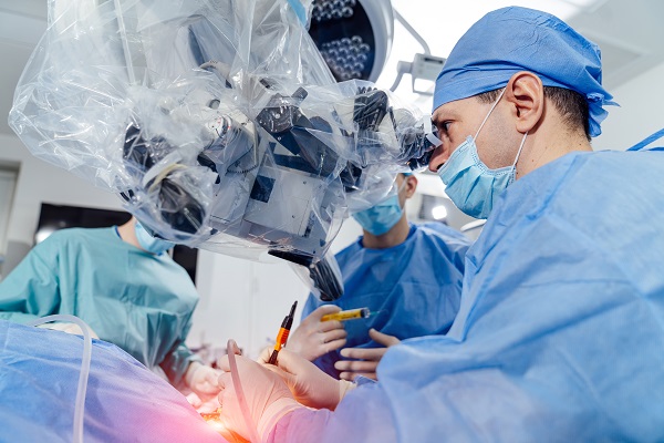 Bloco cirúrgico onde se vê um médico oftalmologista realizando uma cirurgia de glaucoma, acompanhado por 2 auxiliares.