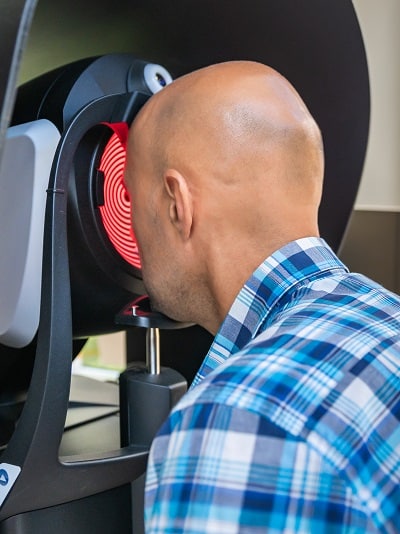 Homem calvo fazendo uma topografia corneana para identificar problemas visuais.
