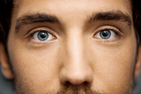 Close da parte superior do rosto de um belo jovem com olhos azuis.