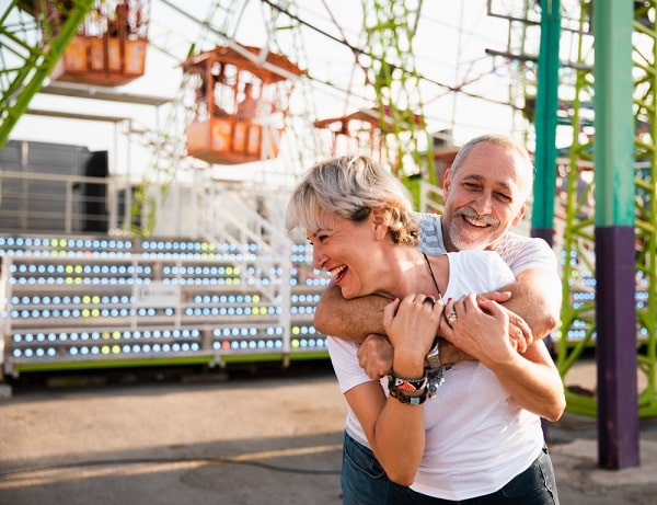 Casal de meia idade divertindo-se em parque de diversões.